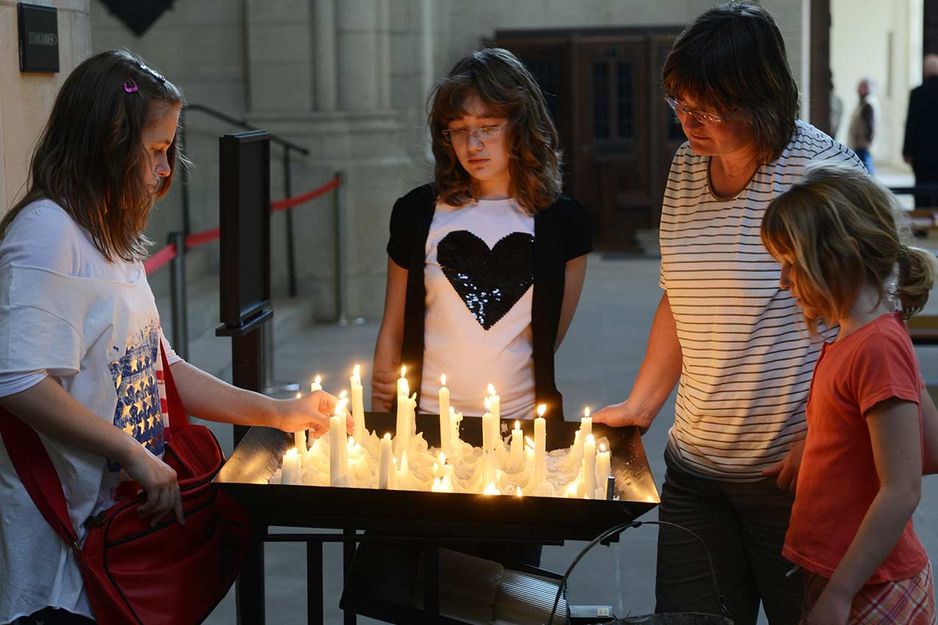 Familie zündet Kerzen für einen Verstorbenen an.